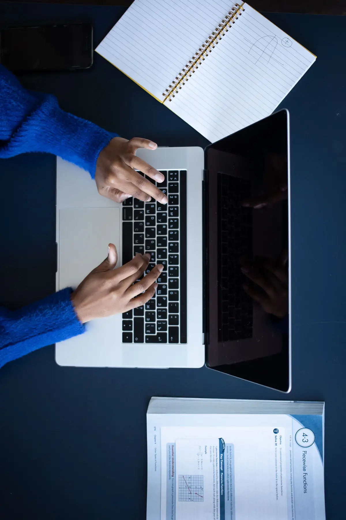 Seseorang mengetik di laptop sambil meneliti informasi